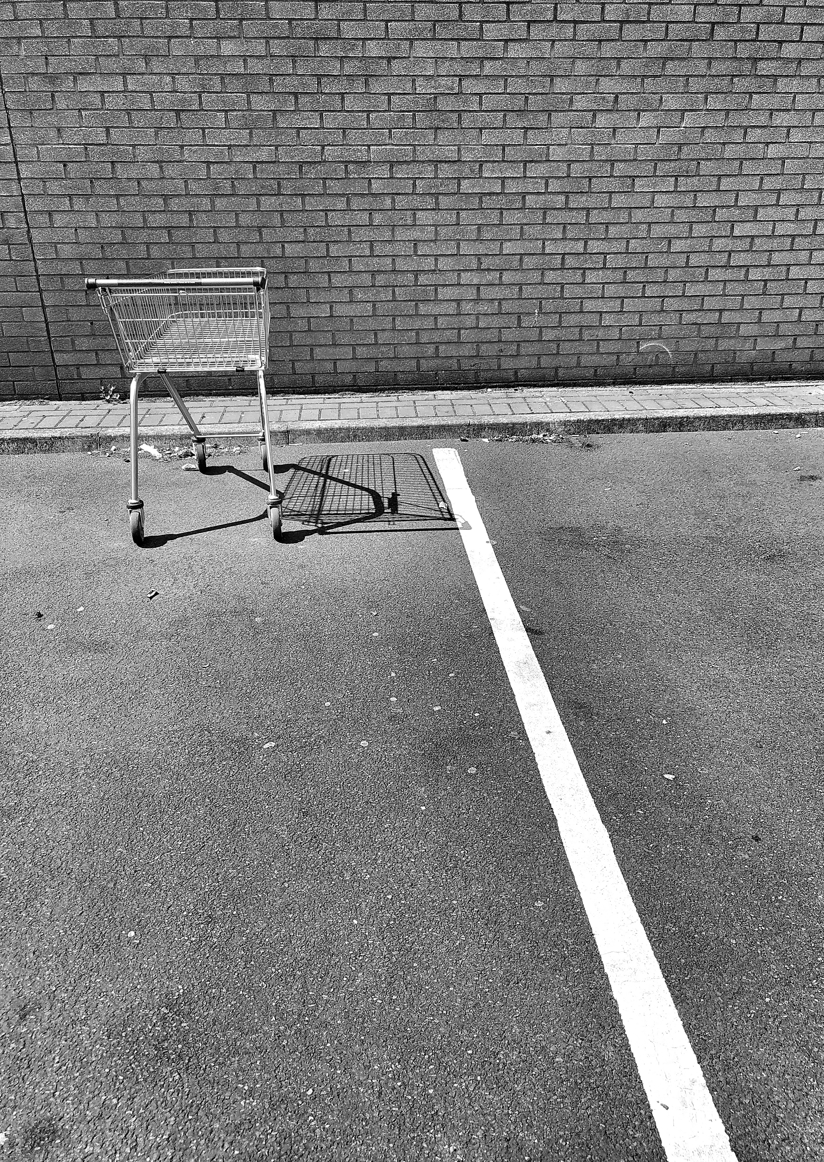 a shopping tolly parked in a car parking space with a shadow cast on the ground